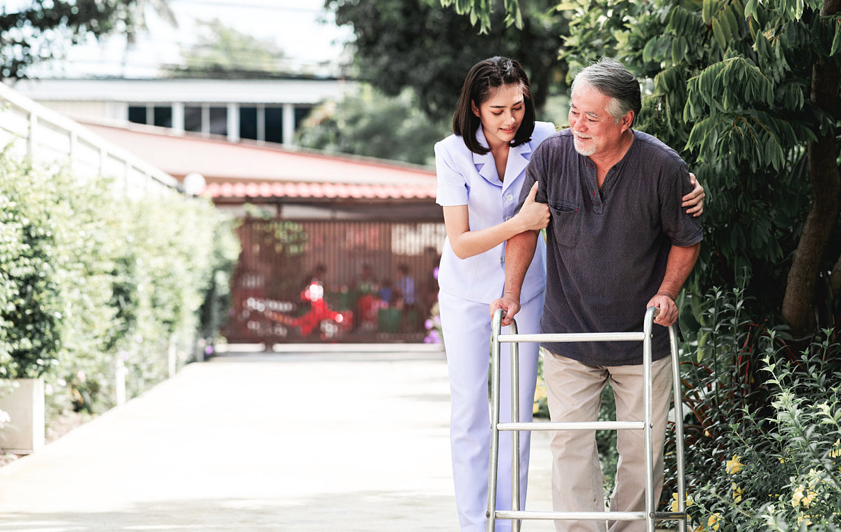 caregiver helping senior man walkt